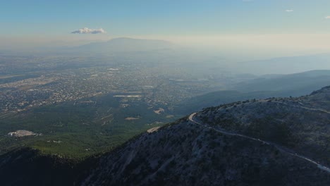 Curved-mountain-road-with-Athens-city-in-the-background---Parnitha