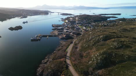 Lakeside-road-to-Kyle-of-Lochalsh-with-ferry-and-Skye-bridge-and-distant-mountains-in-Scottish-Highlands