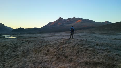 Slow-anticlockwise-pan-of-hiker-against-Black-Cuillin-mountains-at-dawn-on-the-Isle-of-Skye-Scotland