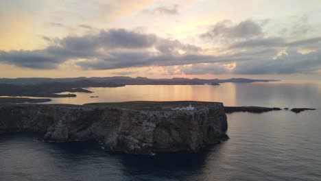 Cavalleria-Lighthouse-north-of-Menorca-sits-with-the-sunsetting-behind-it-on-the-edge-of-a-cliff
