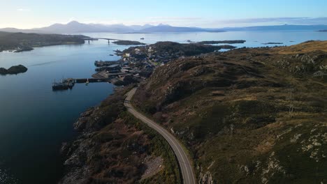 Pan-down-to-lochside-road-to-Kyle-of-Lochalsh-with-traffic-and-Skye-bridge-in-Scottish-Highlands