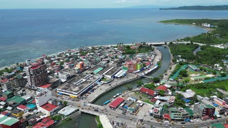 High-Angle-Aerial-View-of-Seaside-town-of-Virac,-Catanduanes,-Philippines-with-busy-traffic-and-open-Ocean-in-background