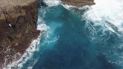 Junger-Mann-Schwimmt-Zum-Ufer-Der-Spitting-Cave-In-Honolulu,-Hawaii-–-Luftaufnahme-Von-Oben-Nach-Unten