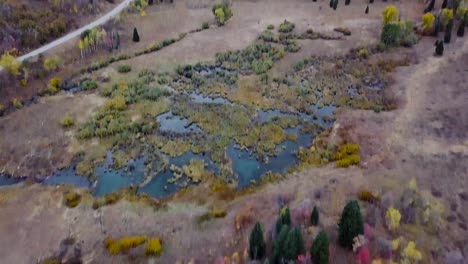 marsh-land-in-snow-basin-utah-with-plenty-of-water-reflections-and-aspen-and-evergreen-trees---AERIAL-DOLLY-TILT