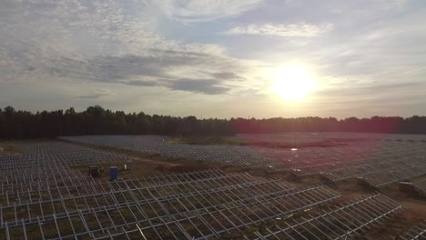 Drone-shot-of-a-solar-field-being-constructed,-into-the-sun