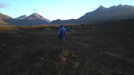 Cuillin-mountains-lit-by-dawn-light-while-hiker-admires-the-view