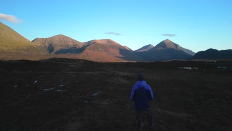 Hiker-silhouette-and-mountain-range-lit-by-dawn-light-on-the-Isle-of-Skye-Scotland