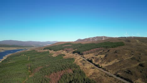 Rise-up-revealing-turning-wind-turbines-and-highland-road-next-to-Loch-Loyne-Scottish-Highlands