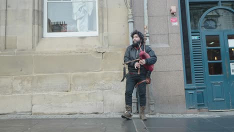 A-street-performer-in-a-typical-UK-City-plays-a-set-of-bag-pipes