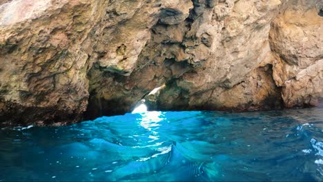 Höhle-über-Türkisfarbenem-Wasser-Mit-Einem-Loch,-Durch-Das-überbelichtetes-Licht-Eindringt-Und-Das-Wasser-Erhellt