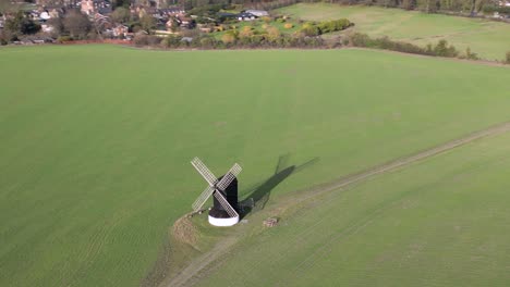 Orbiting-aerial-view-Pitstone-windmill-landmark-high-above-idyllic-Buckinghamshire-rural-agricultural-field-at-sunrise