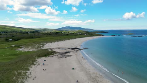 Glassilaun-Beach-Located-in-the-Connemara-region-of-County-Galway,is-a-long-stretch-of-white-sand,-with-a-backdrop-of-rugged-mountains-and-the-bright-blue-waters-of-the-Atlantic-Ocean