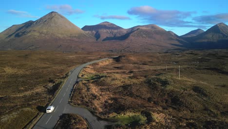 Rise-up-over-highland-road-with-white-van-heading-towards-Red-Cuillin-mountains-on-Isle-of-Skye-Scotland