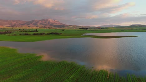 Lake-surrounded-by-green-fields-in-Greece-at-sunset-with-reflections