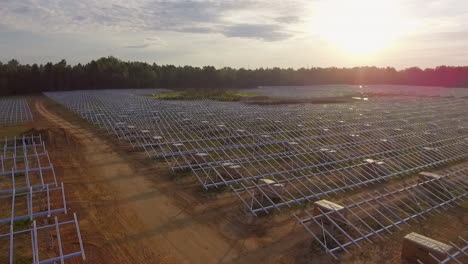 Aerial-shot-of-a-solar-field-being-constructed,-into-the-sun