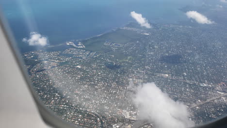 Plane-window-of-ocean-and-beach-coming-into-a-city