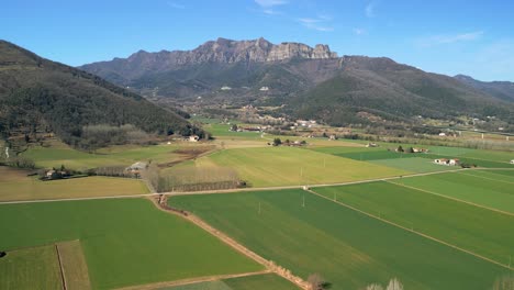 Spectacular-aerial-view-of-La-Garrotxa-in-the-province-of-Girona-cultivated-fields-of-green-color-beautiful-mountain-in-the-background-nature-and-ecology