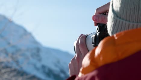 Detail-Kaukasischer-Männlicher-Hände,-Die-Eine-Kamera-Hochhalten-Und-Winterliche-Verschneite-Berglandschaft-Fotografieren