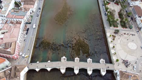 Drone-reveal-shot-in-Tavira-Algarve-Portugal,-pan-from-Ponte-Romana-Bridge-along-the-Galao-River-to-the-Atlantic-Ocean,-also-with-the-salt-lagoon-just-before-the-Sea