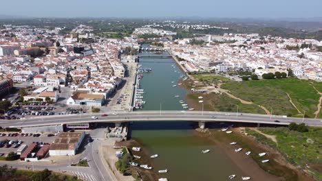 Drohnenaufnahme-Der-Stadt-Taverna-Vom-Ausgang-Des-Hafens-Bis-Zum-Meer,-Portugal-Und-Der-Algarveküste