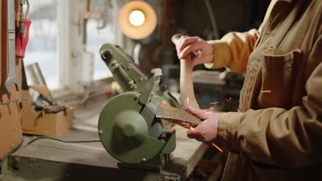 Man-sharpening-an-axe-in-a-workshop