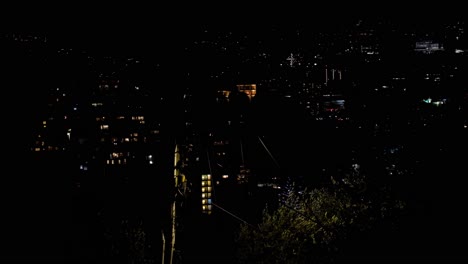 Warm-glow-of-lights-at-night-in-urban-capital-city-Wellington-in-New-Zealand,-Aotearoa,-on-a-windy,-blustery-night-overlooking-dark-cityscape
