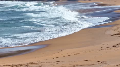 Surf-waves-breaking-along-the-shoreline-of-Cala-Pilar,-Menorca-Spain