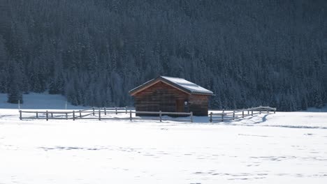 Wooden-cabin-surrounded-by-sonwy-covered-winter-landscape-and-trees-is-background