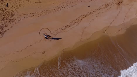 Aerial-view-of-person-drawing-love-heart-in-the-sand-along-a-beach-in-Spain