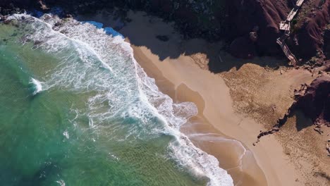Top-down-view-of-beach-with-waves-calmly-lapping-the-shoreline