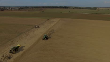 Farmer-moving-large-industrial-farm-equipment-along-dirt-road