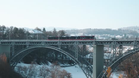 Red-tram-passing-over-a-bridge-and-a-sunny-winter-day-in-Bern,-Switzerland