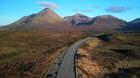 Flying-along-highland-road-towards-Red-Cuillin-mountains-at-dawn-with-single-van-at-Sligachan-on-the-Isle-of-Skye-Scotland