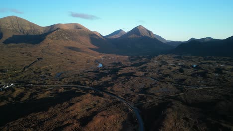 Weitläufige-Höhenaufnahme-Der-Schottischen-Moorlandschaft-Und-Der-Hochlandstraße-Mit-Den-Roten-Cuillin-Bergen-Bei-Sonnenaufgang-In-Sligachan-Auf-Der-Insel-Skye-In-Schottland
