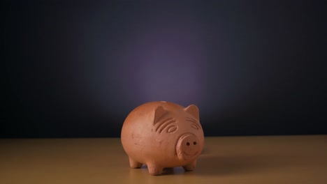 Hand-of-a-white-man-putting-coin-in-a-clay-piggy-bank