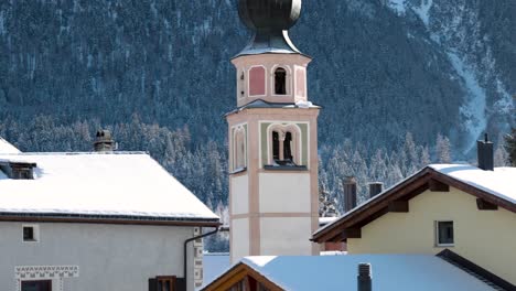 Traditional-church-and-houses-in-a-swiss-village-with-mountains-in-the-background-in-Switzerland