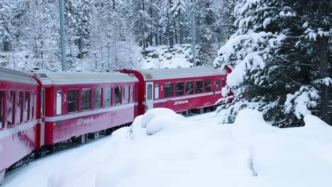 Blick-Auf-Einen-Roten-Zug,-Der-Durch-Einen-Wald-Und-Eine-Schneebedeckte-Winterlandschaft-Fährt