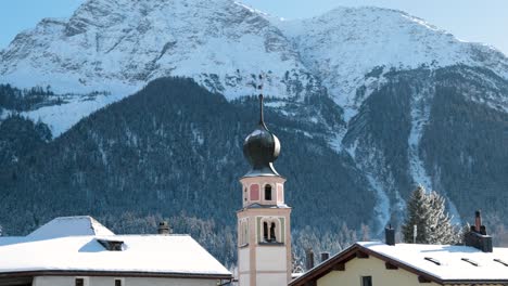 Traditional-church-and-houses-in-a-swiss-village-with-mountains-in-the-background-in-Switzerland