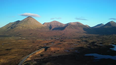 Flying-over-highland-road-with-Red-Cuillin-mountains-glowing-in-sunrise-at-Sligachan-on-the-Isle-of-Skye-Scotland