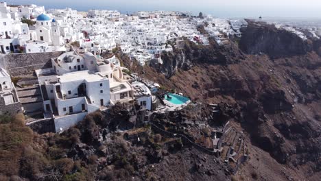 Dramatische-Rotierende-Luftaufnahme-Der-Architektur-Von-Santorini-Und-Blick-Auf-Die-Klippen,-Imerovigle,-Griechenland