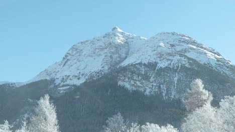 Autoblick-Auf-Schneebedeckte-Berggipfel,-Bäume-Und-Nebel-An-Einem-Sonnigen-Morgen-In-Der-Schweiz