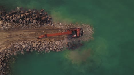 Construction-of-a-new-breakwater-by-Excavator-machine,-top-down-view