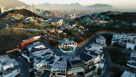Aerial-view-over-rich-and-poor-homes-in-the-mountains-of-Monterrey,-sunset-in-Mexico
