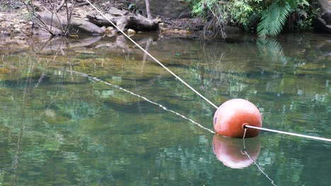 Orange-buoy-floating-on-clear-water.-DOLLY-OUT
