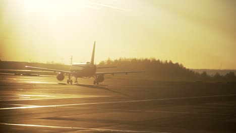 Silhouette-of-airplane-on-airport-runway-during-morning-sunrise-light