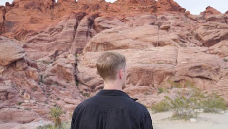 Young-caucasian-man-walking-in-slow-motion-in-Red-Rock-Canyon-National-Conservation-Area-in-Nevada,-USA