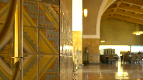 Pan-right-along-the-main-entrance-hall-with-travelers-walking-through-Union-Station-in-Los-Angeles,-California