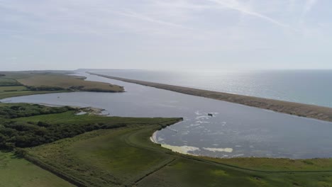 Aerial-tracking-from-left-to-right-with-a-slight-rotation-looking-over-the-fleet-lagoon-at-Abbotsbury,-Dorset