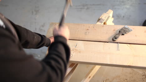A-wide-angle-shot-of-a-person-hammering-nails-into-a-wooden-plank