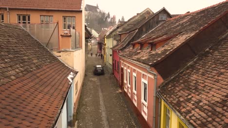 Car-passing-by-stone-street-of-the-famous-Sighisoara-medieval-town-with-the-church-on-the-top-of-the-hill-in-background